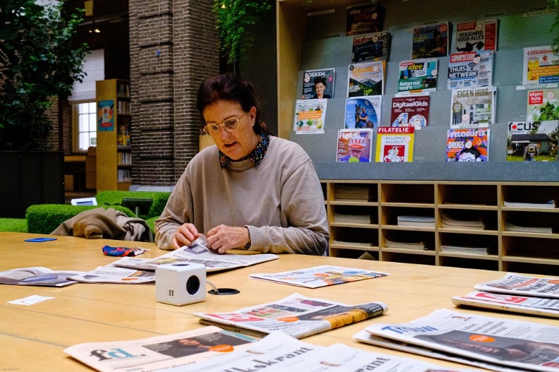  Mevrouws leest tijdschrift aan leestafel in de Korenbeurs